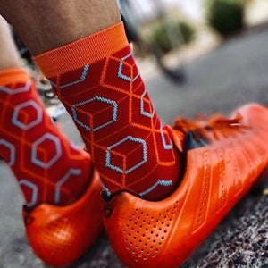 Cyclist wearing Beehive socks with matching orange cycling shoes.
