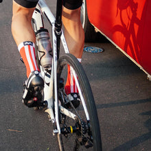 Load image into Gallery viewer, Cyclists rides past a red van with Red Racer socks